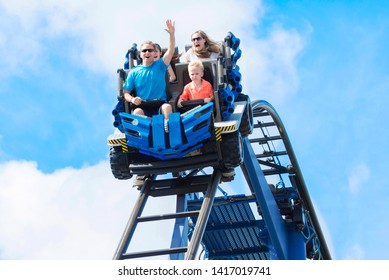 Young family having fun riding a rollercoaster at a theme park. Screaming, laughing and enjoying a fun summer vacation together.