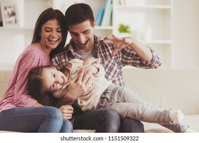 Young Family Having Fun. Together at Home. Happy Childhood. Attractive Young Couple. Parents and Kid Sitting on Sofa. Portrait at Home. Family Concept. Smiling Parents. Child at Home.
