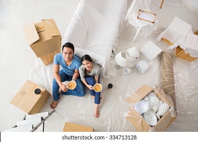 Young Family Having Lunch After Unpacking In New Flat