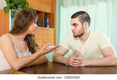 Young Family Having Serious Talking At The Table In Home