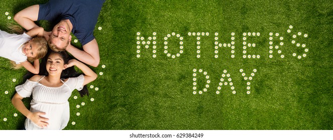 Young Family Laying In The Grass On Mothers Day