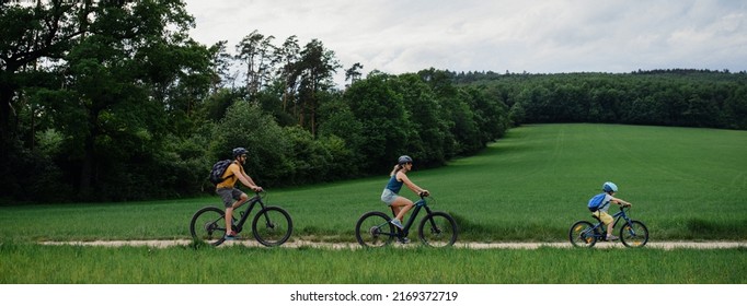 Young family with little child riding bicycles on path in park in summer. - Powered by Shutterstock