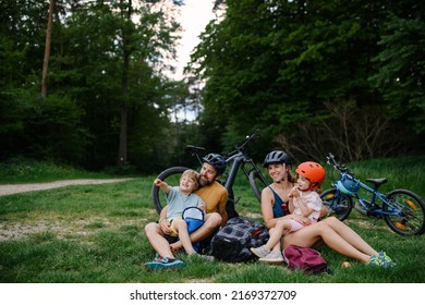 Young family with little children resting after bike ride, sitting on grass in park in summer. - Powered by Shutterstock