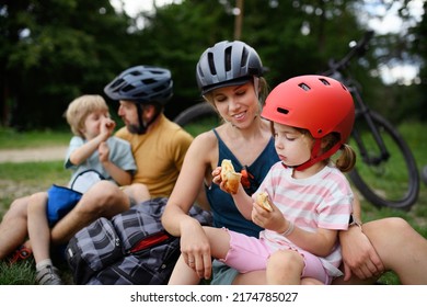 Young family with little children resting after bike ride, sitting on grass in park in summer. - Powered by Shutterstock