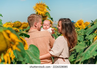 A Young Family With A Little Cute Baby In A Field Of Sunflowers. Happy Summer, Family Activities And Outdoors Lifestyle.