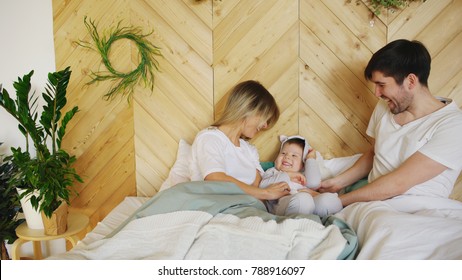 A young family with little son play on bed in the bedroom