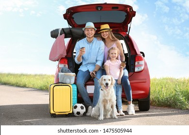 Young Family With Luggage And Dog Near Car Trunk Outdoors