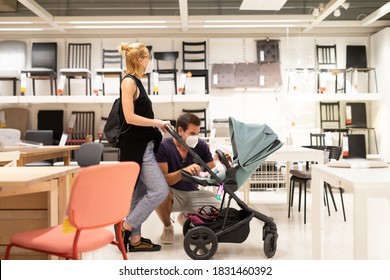 Young Family With Newborn In Stroller Shopping At Retail Furniture And Home Accessories Store Wearing Protective Medical Face Mask To Prevent Spreading Of Corona Virus When Shops Reopen.