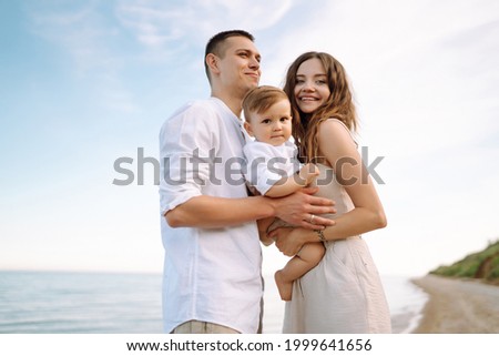 Young family on the beach. People are having fun on summer vacation. Father, mother and child against the background of the blue sea and sky. Travel, active lifestyle, vacation, rest concept.