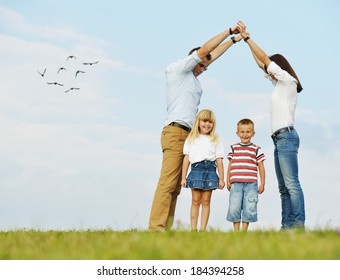 Young Family On Green Summer Grass Meadow Building Dream New Home