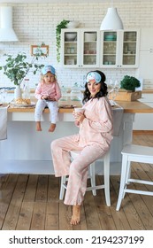 Young Family In Pajama, Sleep Mask Having Breakfast Together. Mother, Little Daughter Eating Healthy Food In Morning At Kitchen. Toddler Kid Using Phone Watching Cartoons. Child Addiction From Gadgets