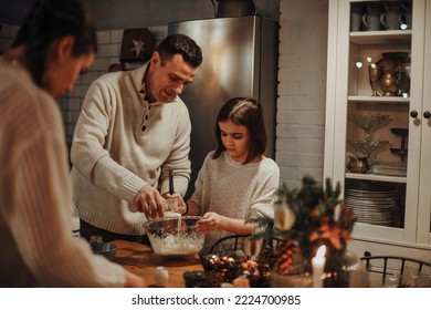 Young family, parents and child cooking homemade cake together in cozy kitchen at home during winter holidays, father helping daughter to prepare dough for pie. Cooking with kids - Powered by Shutterstock