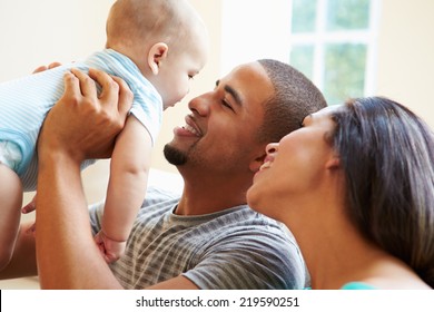 Young Family Playing With Happy Baby Son At Home