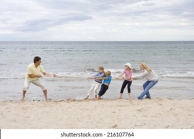 Young Family Playing Tug Of War At Beach