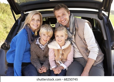 Young Family Pose Together At Rear Of Car