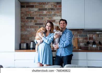 Young Family, Pregnant Woman And Her Partner Or Husband With Dog And Cat At Kitchen