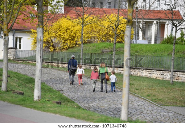 A\
young family returns from their day trip in Berlin-Stahnsdorf. A\
young father with his child in front of a young mother with her two\
children are walking on a pathway in\
Berlin-Germany.