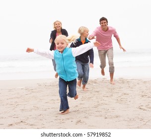 Young Family Running Along Winter Beach