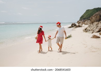 Young family in Santa hats during Christmas vacation walk together by the sea - Powered by Shutterstock