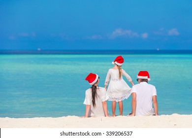 Young Family In Santa Hats During Christmas Vacation