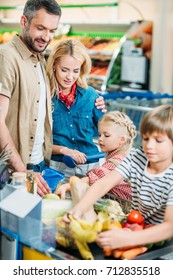 Young Family With Shopping Cart Full Of Purchases In Supermarket