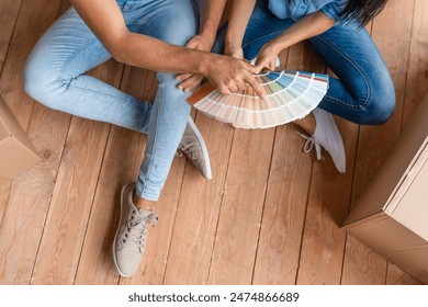 Young family sitting on the floor and choosing color together for their room in new apartment. Couple choosing the perfect paint color for their cozy home, casually sitting in the living room. - Powered by Shutterstock