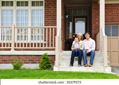 Young Family Sitting On Front Steps Of House