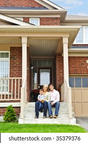 Young Family Sitting On Front Steps Of House