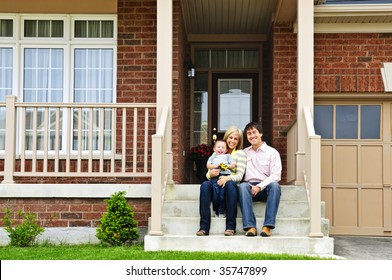 Young Family Sitting On Front Steps Of House