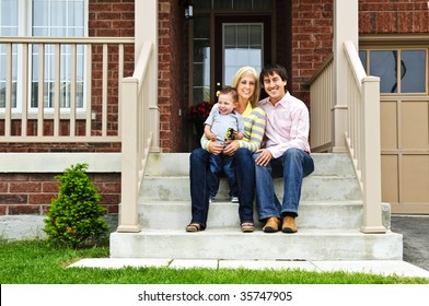 Young Family Sitting On Front Steps Of House