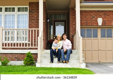 Young Family Sitting On Front Steps Of House