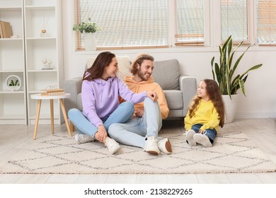 Young family sitting on soft carpet at home - Powered by Shutterstock