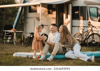 a young family is sitting on a sup board next to their mobile home. - Powered by Shutterstock