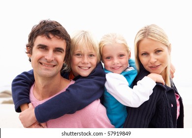 Young Family Sitting On Winter Beach