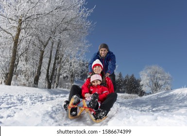 Young Family Sledding On Winter Day