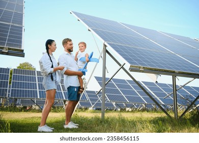 Young family with a small child in her arms on a background of solar panels. A man and a woman look at each other with love. Solar energy concept - Powered by Shutterstock