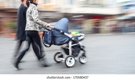 Young family with small children and a pram walking down the street. Intentional motion blur