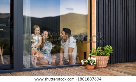 Young family with small daughter indoors, weekend away in container house in countryside.