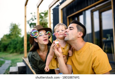 Young Family With Small Daughter Outdoors, Weekend Away In Container House In Countryside.