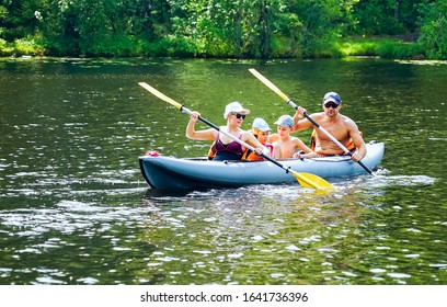 A Young Family With A Son And Daughter Are Kayaking On The Lake