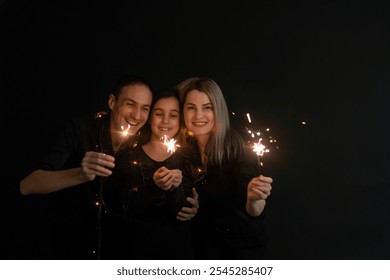 Young family with sparklers at Christmas time on a black background - Powered by Shutterstock