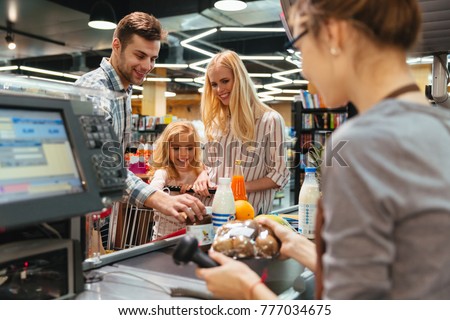 Young family standing at the cash counter buying groceries at the supermarket
