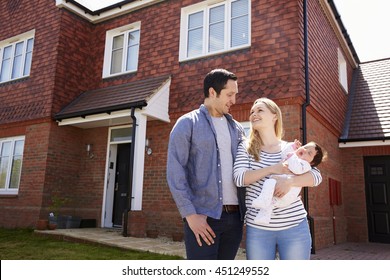 Young Family Standing Outside New Home