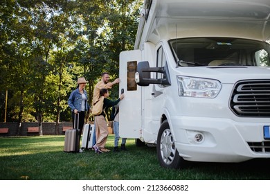 Young Family With Suitcases Entering Caravan Outdoors At Park.