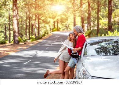 Young Family In Sweaters And Hats Holding Paper Map Traveling La Palma Island By Rented Car In The Forest