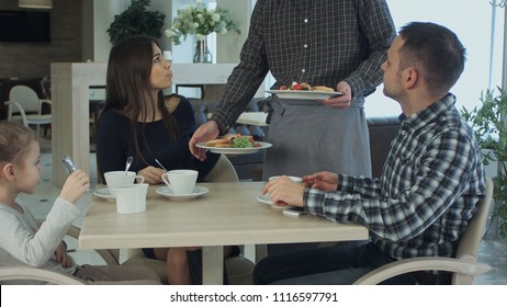 Young Family Take A Meal In Cafe Or Restaurant. Waiter Make A Mistake And Confuse Dishes. Father And Mother Looking Angry And Disappointed.