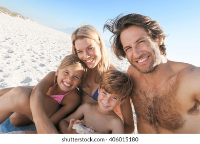 Young family taking selfie in a summer holyday at beach. Portrait of family on summer beach holiday looking at camera. Mother and father with two childreen taking photo at beach. - Powered by Shutterstock