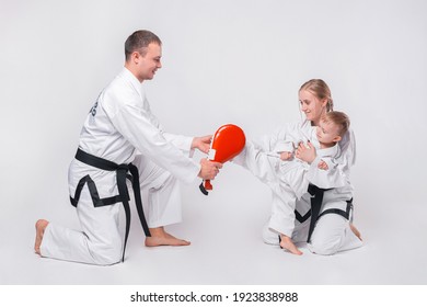 Young family with their little boy practicing martial arts over white background