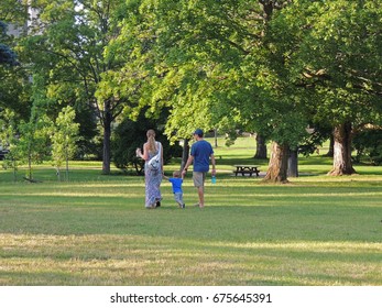 Young Family Of Three Walking In The Park Shot From Behind