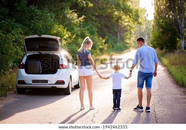 Young family travels by car. Dad, mom and\
son take a break from driving a car and\
walk.